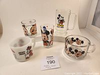 Full set of 5 Mickey and Minnie Mouse glassware items grouped together: various glass cups, mugs, and a clear soup bowl with colorful Disney characters.