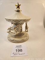 Full view of Mikasa musical carousel with white and gold porcelain design and gold star on top.
