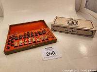 Full view of open chess box with all 32 pieces secured inside, box cover placed beside set