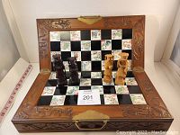 Board opened, both light and dark wood chess pieces positioned on playing surface