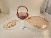 Overview of three pink vintage glass items: octagonal candy dish with handles, round cake platter, and ruffled basket dish with handle.