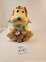 Front view of the Pound Puppy cookie jar featuring the dog holding a teddy bear with green collar.