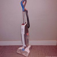 Front angle view of Hoover Power Dash hard floor cleaner showing handle, power cord, and cleaning head with transparent brush compartment.