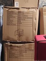 Photo of the cardboard boxes showing packaging details and quantity for two single chair cushions measuring 69x81x80 cm labelled made in China.