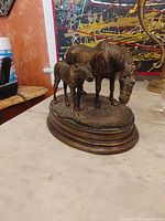 Photo of bronze sculpture showing two horses, an adult and a foal, on an oval bronze base with signature visible.