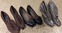 Three pairs of ladies shoes in size 7: brown suede heels, black low-heel flats, and light brown ankle boots arranged on floor
