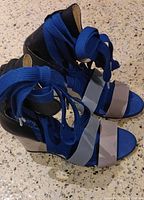 Blue Adidas wedge sandals with blue fabric lace-up straps lying on speckled countertop