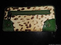 Photo showing the front exterior of the JUICY COUTURE wallet with leopard print and green leather accents, including a zippered pocket.