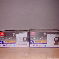 Photo showing two boxed Globe 4 inch LED recessed lighting kits, each indicating 50W LED bulbs included, 400 lumens, dimmable and 3000K color temperature.