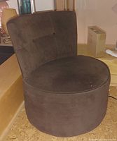Front and side view of the brown mid-century modern swivel chair showing rounded seat and tufted backrest, with minor stain on seat.