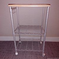 Front view of the 3-tier utility trolley showing metal frame, wire mesh shelves, wooden top, and caster wheels.