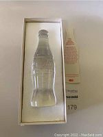 Full lead crystal Coca-Cola bottle in original box with protective foam insert and authenticity card explaining the piece's significance and production.