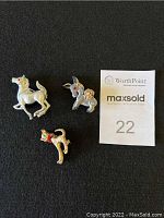 Three animal brooches on black background with a paper tag marked 22