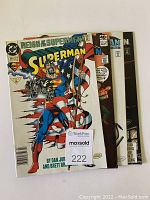 Four Superman comic books stacked together showing partial covers, seller tag visible