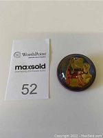 Top-down photo showing brooch and auction tag number 52