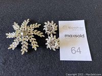 Full set showing the brooch and two matching clip-on earrings on black surface with a MaxSold lot card.