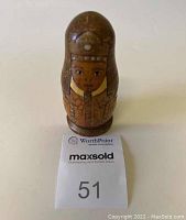 Large wooden nesting doll painted with Egyptian Pharaoh imagery, dome-shaped top with golden and brown tones, face with detailed eyes and mouth, standing upright on white surface with Maxsold tag.