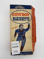 Original box with vintage cowboy marionette graphic and wear on edges