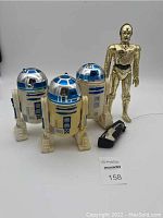 Group image showing 3 R2-D2 figures and 1 C3-PO figure with remote control for one R2-D2.