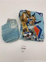 Folded blue fitted sheet and pillowcase with Star Wars The Empire Strikes Back characters and logos.