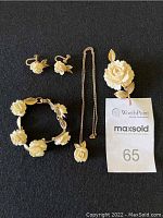 Full set of vintage Krementz white rose gold-tone women's jewelry, comprising necklace with pendant, bracelet, screw-back earrings, and brooch on a black background.