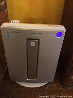 Front view of Sharp air cleaner showing LED indicators lit and operational status with blue light on the upper right side.