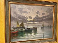 Framed oil painting showing multiple boats on water with cloudy sky.