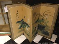 Front view of folding screen showing painted leaves, flowers, birds, and calligraphy details on three hinged panels with patterned borders.