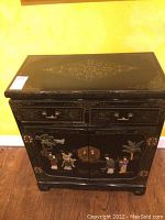 Front view of entire cabinet showing drawers, doors, decorative figures and brass hardware