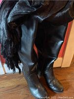 Photo of the black tall leather boots, showing smooth leather material and rounded toe.