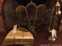 Fan-style brass fire screen, curved and decorative with detailed feet, positioned in fireplace backing.