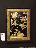 Frontal view of the artwork mounted on the wall featuring birds and floral elements in pearl inlay with gold-textured frame.