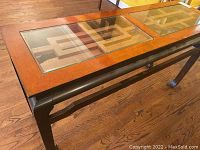 Full view of rectangular oriental style side table with wooden frame, glass top inset showing geometric design beneath glass, and darker base and legs.