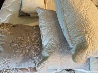 Five pillows and four cushions stacked on a bed mattress