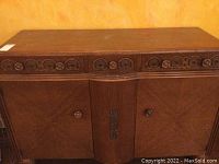 Front view of vintage wooden sideboard showing carved drawer fronts and doors