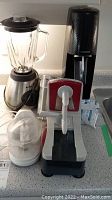 Overview of all items on countertop including Sodastream, blender, food processor attachment, and electric slicer