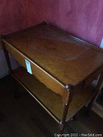 Wooden tea trolley with top and lower shelves, showing overall front side view and wheels.