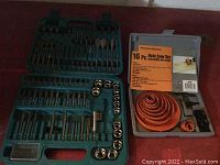 Green plastic case containing a variety of drill bits and sockets organized in compartments.