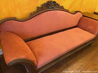 Full view of the vintage sofa showing wooden frame and reddish-pink upholstery.