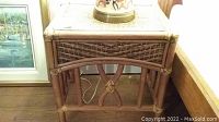 Front view of a wicker bedside table showing woven wicker top and decorative frame.
