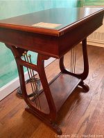 Full view of the dark wood side table with curved sides and storage top.