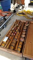 Open wooden case showing 6 mallets and 6 balls with colored bands inside the vintage croquet set.