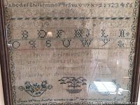 Frontal photo of the antique sampler showing alphabets, numbers, floral basket, inscription dated 1836