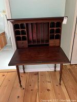 Front view of desk with drop-down surface lowered, showing upper cubbyholes, vertical letter slots, and drawers.