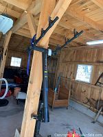 Image showing the full view of the Outback bike rack hanging from wooden support beam in a barn, visible four arm hooks for bike support.