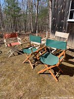 Four director's chairs outdoors: two green fabric chairs, one orange fabric chair, one beige seat chair missing backrest, wood frames weathered.