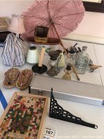 Photo showing all items including pink Japanese parasol, straw slippers, glass bottle, candle holders, cribbage game frame, and other decorative objects.