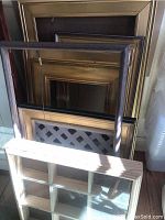 Seven gold-tone picture frames stacked together showing different gold finish styles and wire hangers.