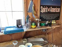 Blue plastic carrying case on wooden shelf with other tools and hardware around, containing assorted screwdriver bits and nut drivers inside case compartments.