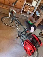 Photo showing the full bicycle with red saddlebags on rear rack, visible in barn environment.